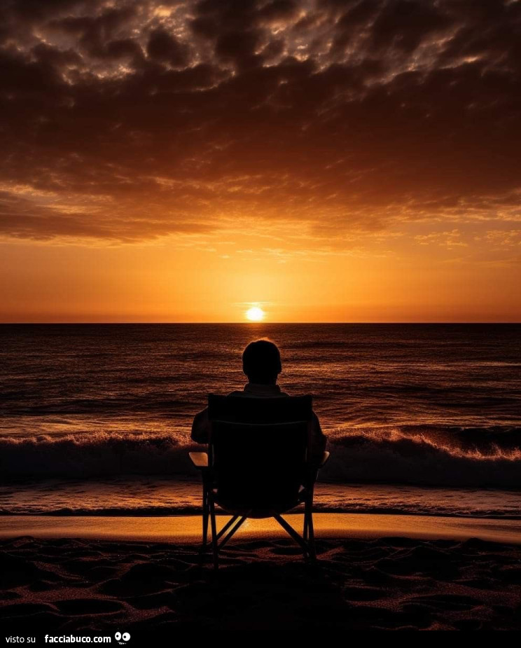 Seeduto sulla spiaggia a guardare l'alba